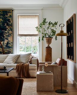 Cozy living room with striped sofa, leather chairs, large window, plants and neutral decor