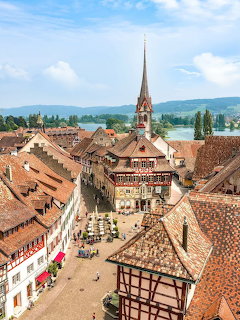 Aerial view of a medieval European town with half-timbered houses, church spire, and river