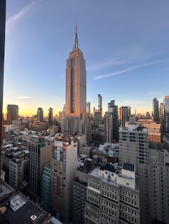 Empire State Building towering over Manhattan skyline at sunset with orange and blue sky