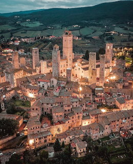 Aerial view of San Gimignano medieval town with stone towers illuminated at dusk in Tuscany, Italy