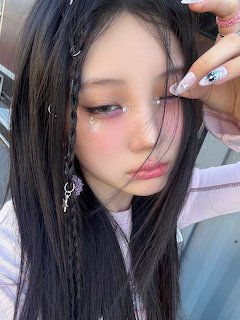 Close-up selfie of young woman with glitter makeup, pink blush, dark hair and silver earings