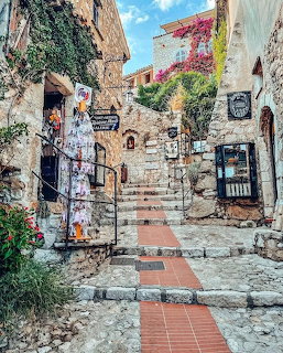 Stone stairway in a Mediterranean village with shops, bougainvillea, and a red-tiled walkway