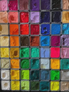 Top-down view of a watercolor paint palette with rows of colorful square paint pans