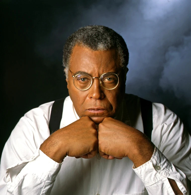 Studio portrait of James Earl Jones resting his chin on his hands against a dark background