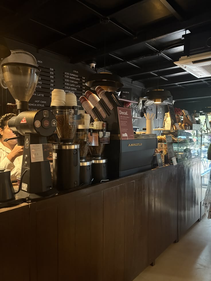 Interior of a café with multiple coffee grinders and espresso machines on a dark wooden counter