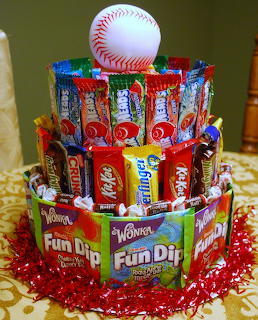 Three-tier candy cake with baseball on top, decorated with chocolate bars and colorful sweets