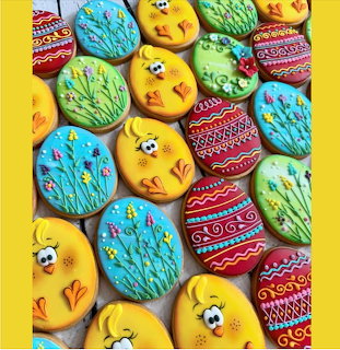Colorful decorated cookies shaped like Easter eggs and yellow chicks on a yellow background