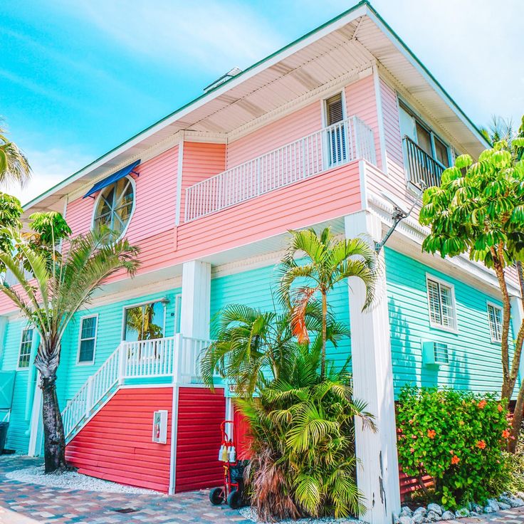 Bright pink and turquoise tropical house with palm trees and red stairs
