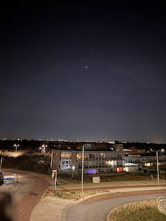 Night view of a curved road, streetlights, and a low building beneath a dark sky.