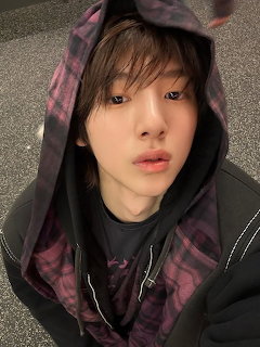 Close-up of a young person in a dark hoodie with purple plaid lining, looking up at the camera.