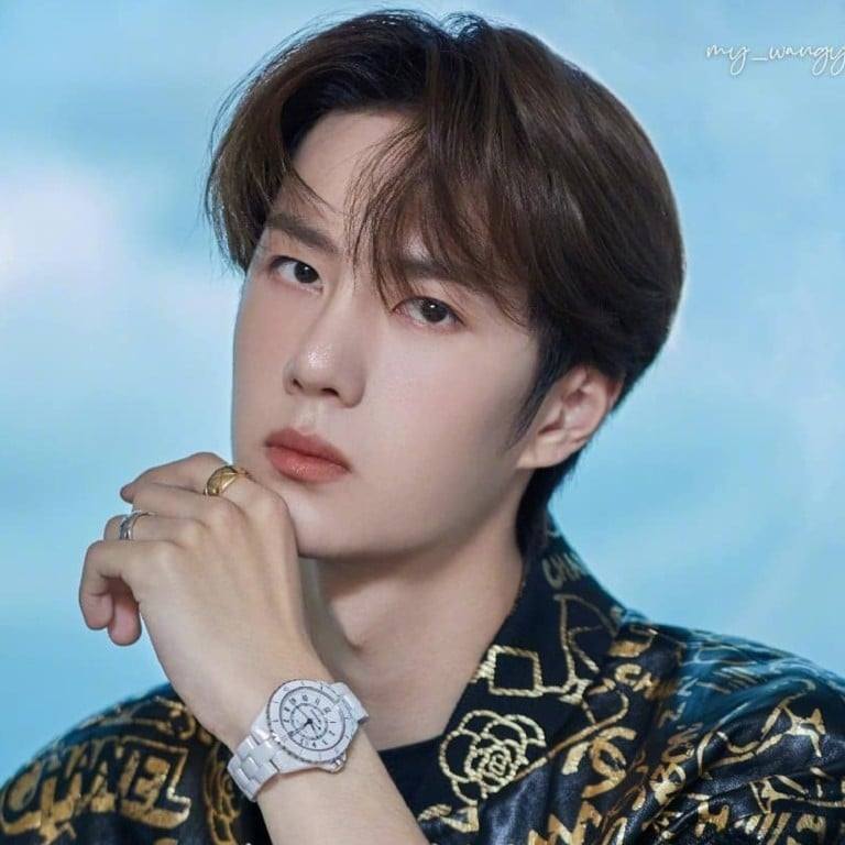 Young Asian man in patterned shirt with white watch posing against blue background