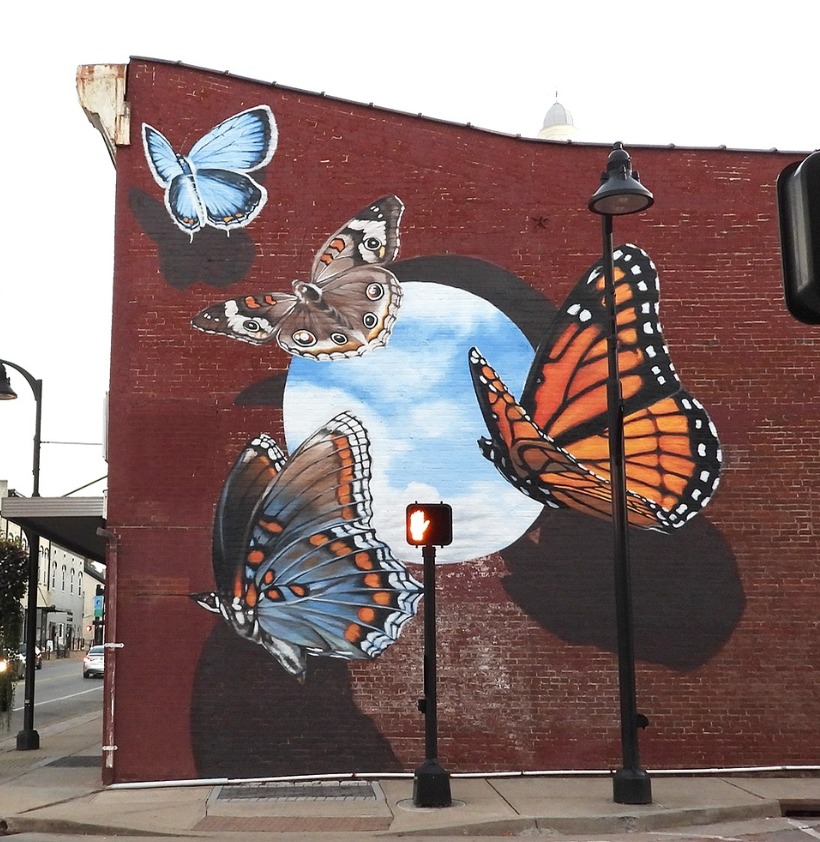 Colorful butterfly mural painted on a brick wall beside a city street