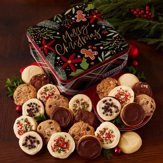 Variety of Christmas cookies arranged in front of festive holiday tin with evergreen branches and red berries