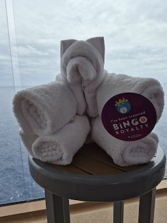 White towel folded into an elephant shape on a stool with ocean visible through a cruise ship balcony