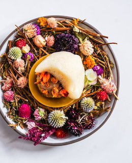 Autumn wreath of dried flowers and natural elements arranged around a glowing candle on a plate