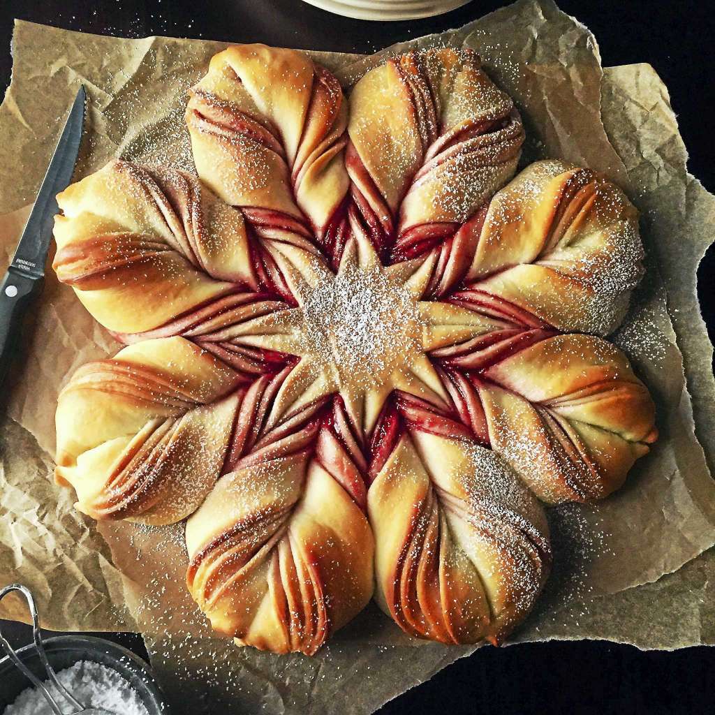 Star-shaped artisan bread with twisted chocolate-filled segments on parchment, viewed from above
