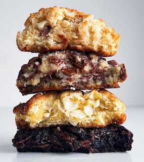 Stack of four chocolate chip cookies with different textures and chocolate varieties on white background