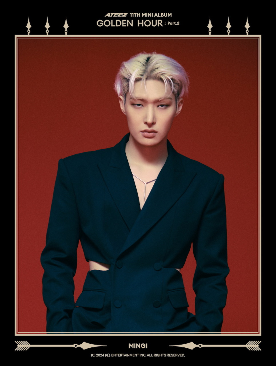 Portrait of K-pop artist Mingi with platinum blonde hair wearing dark formal jacket against red background