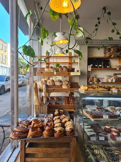 Bakery interior with shelves of fresh pastries and breads near a street-facing window