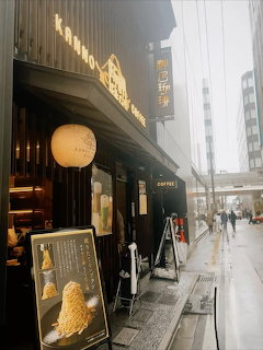 Cozy coffee shop entrance with glowing lanterns on foggy Kyoto street at dusk
