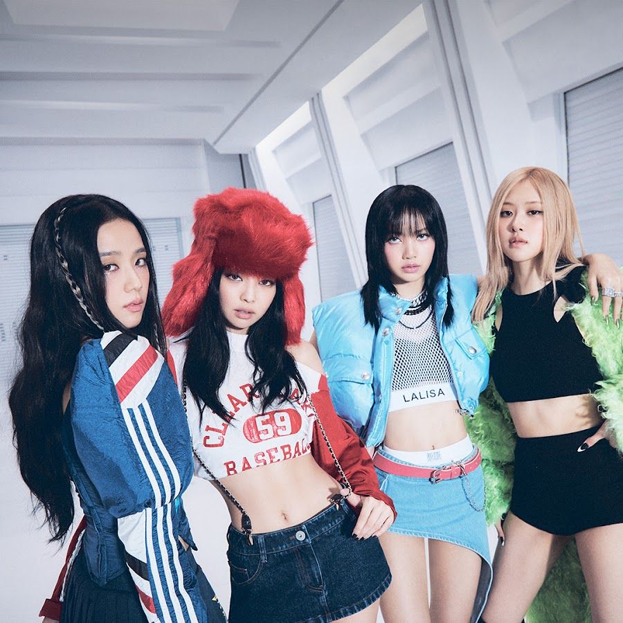 Four women in trendy streetwear posing in a white modern room