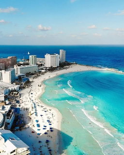 Aerial view of Cancún beach with turquoise water, white sand, and resort hotels along the coast