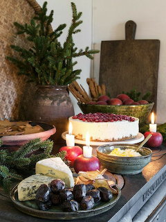 Christmas dessert spread with cheesecake, stollen, cookies, plums, and evergreen decorations on wooden table