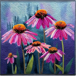 Fabric art quilt showing pink echinacea coneflowers with stems on blue quilted background