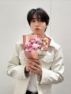 Young man in white blazer holding pink flower bouquet