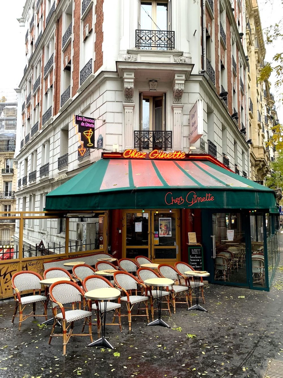 Corner cafe in Paris with striped awning and outdoor seating on cobblestone street