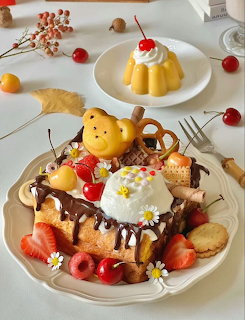 Cute bear-shaped pancakes with berries, whipped cream, waffles, and pudding on decorative plates