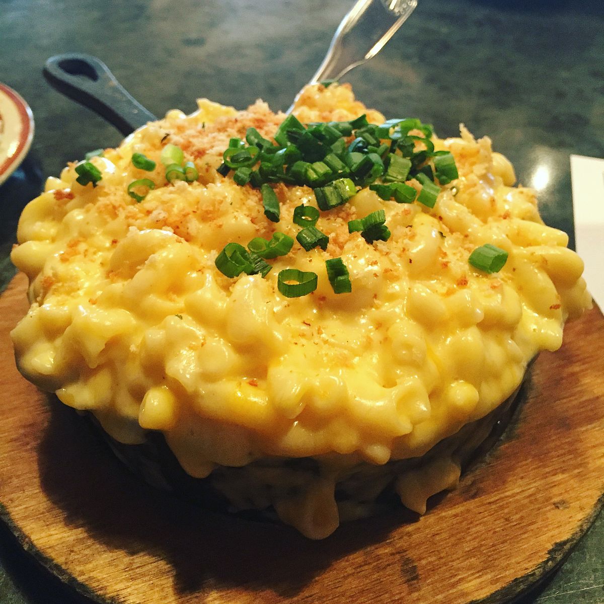 Creamy mac and cheese garnished with chopped chives in a black skillet