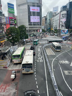 Aerial view of Shibuya crossing in Tokyo with buses, vehicles, and commercial buildings