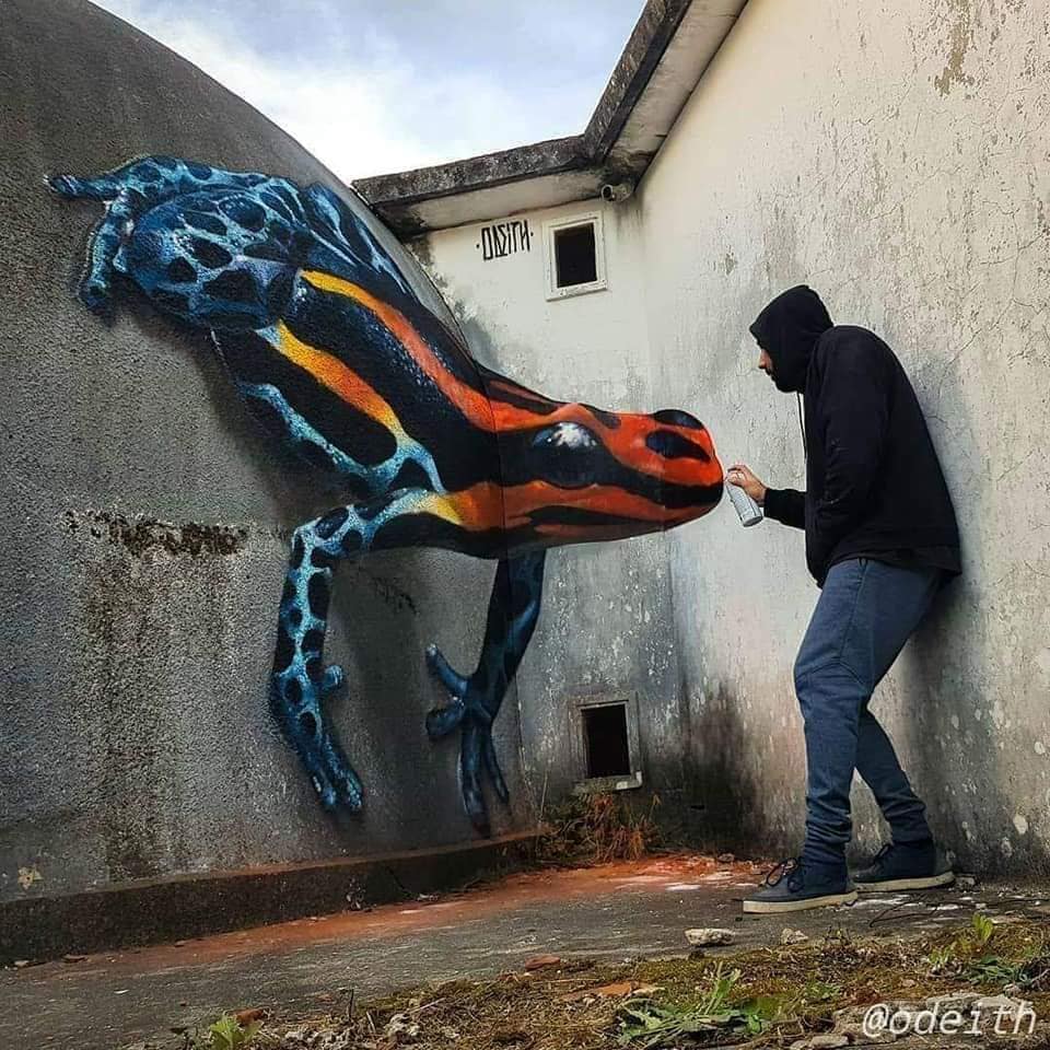 Hooded person next to a large colorful salamander mural on worn alley walls