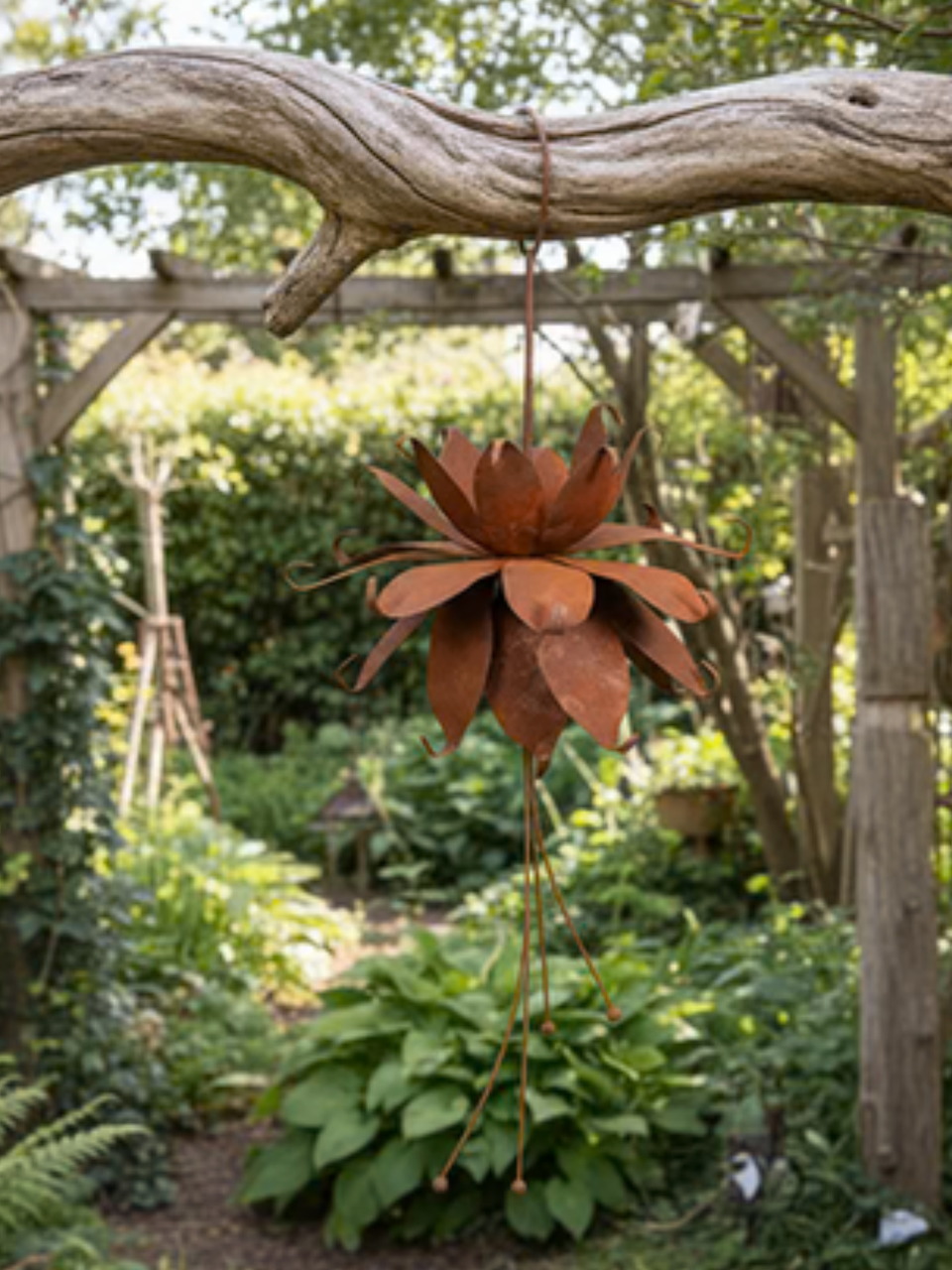 Rusty metal flower hanging ornament suspended from a wooden garden arch surrounded by green foliage