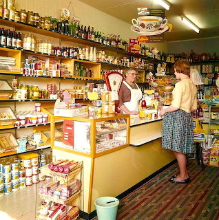 Interior of traditional Dutch grocery store with shelves of products, customer and shopkeeper at wooden counter