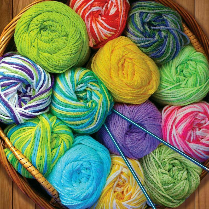 Colorful balls of yarn in bright colors arranged in a wooden box with knitting needles