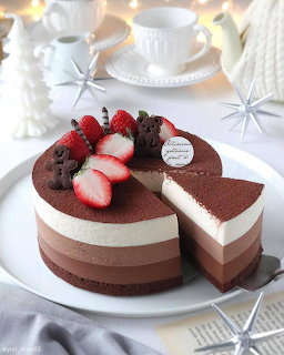 Layered chocolate mousse cake with strawberries on a white plate and one slice removed