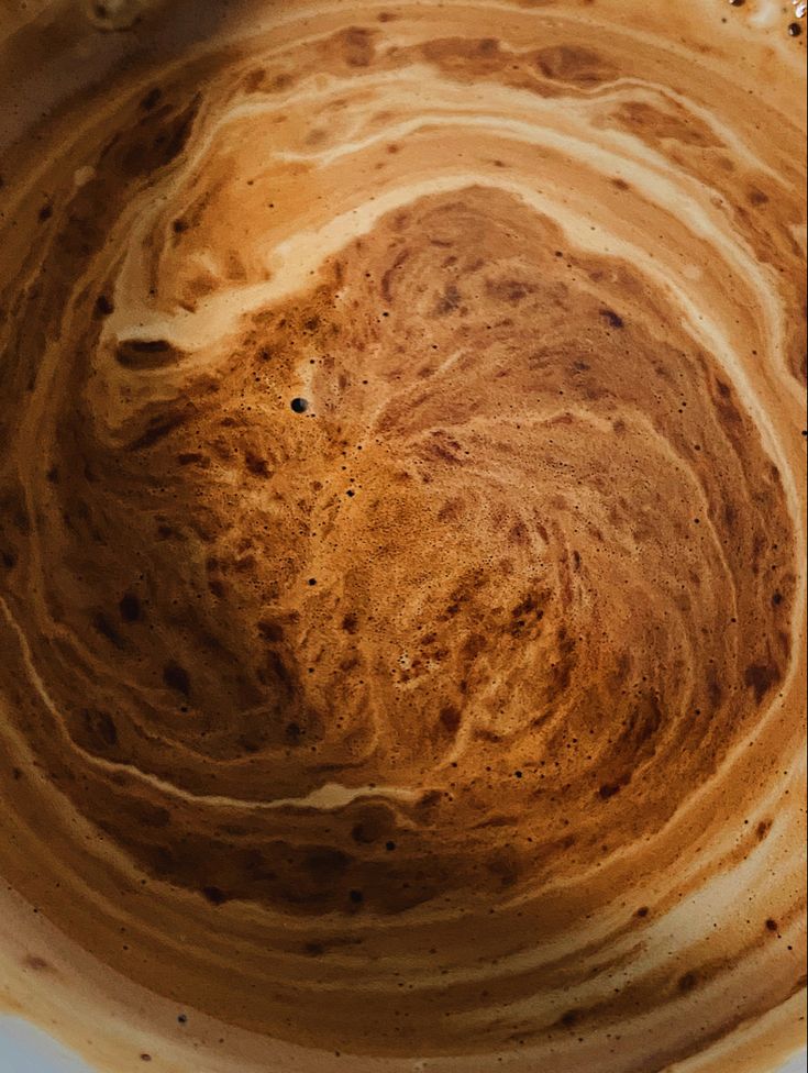 Close-up of swirling coffee foam and crema with abstract brown patterns