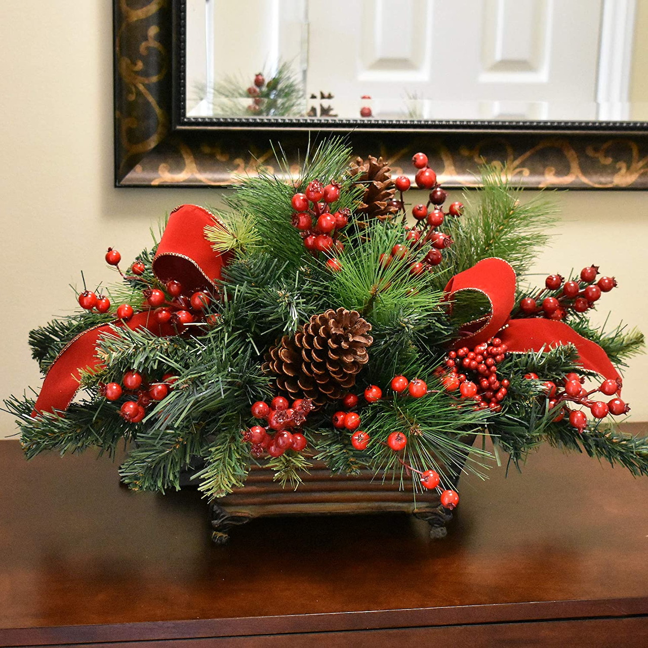 Christmas centerpiece with evergreen branches, red berries, pinecones and cardinal birds in bronze planter