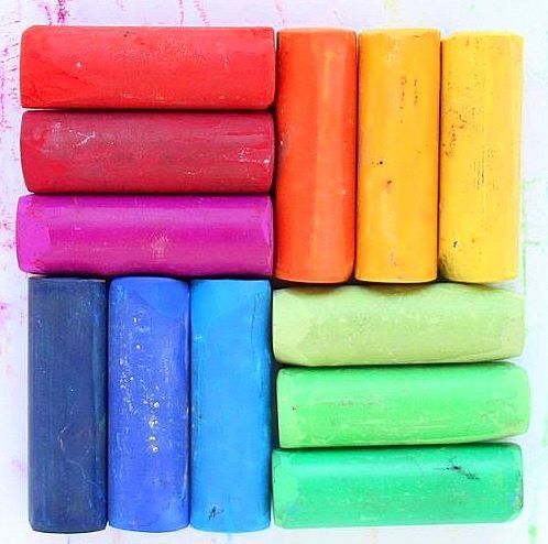 Twelve colorful chalk or pastel sticks arranged in a 3x4 grid showing rainbow colors