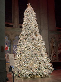Large white origami Christmas tree illuminated with lights inside a cathedral