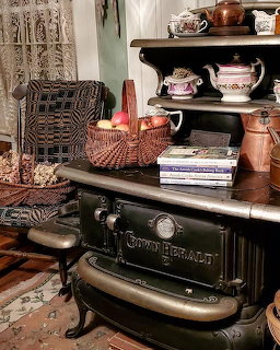 Antique cast iron stove with wicker baskets and copper pots in a rustic interior