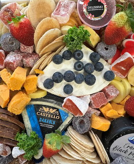 Overhead view of a charcuterie board with cheses, crackers, blueberries, strawberries, meats, and fruits