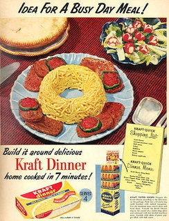 Vintage food ad featuring molded cheese dinner ring with hot dogs and vegetables on red tablecloth