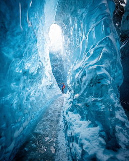 Path inside a blue ice cave with bright light overhead and textured frozen walls
