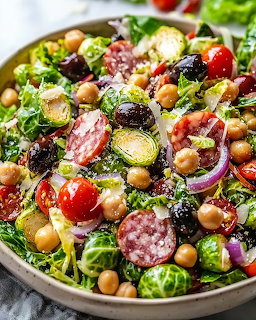 Bowl of Brussels sprout salad with chickpeas, salami, tomatoes, olives, and red onion