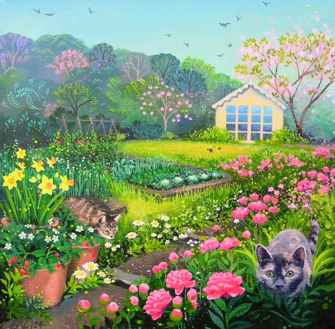 Two cats in a colorful spring flower garden near a yellow cottage