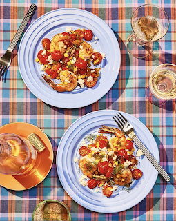 Overhead view of two bruschetta plates with tomatoes and cheese on plaid tablecloth with wine glasses