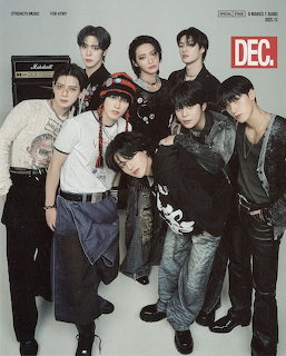 Studio portrait of seven young men in coordinated fashion outfits posing together against a plain background.